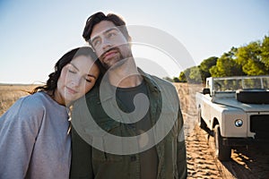 Couple standing by off road vehicle on field