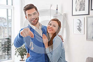 Couple standing at real estate sales office hugging holding keys