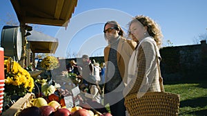 Couple standing at the stall with fruits and vegetables