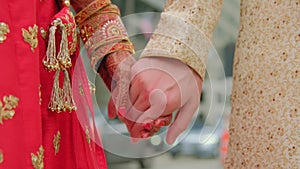 Couple standing together dressed in traditional Indian clothes and holding hands, hindu wedding.