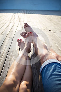 A couple stands barefoot on the wooden pier on the sea, view from the top, legs closeup