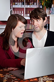 Couple staring in disbelief at a computer laptop