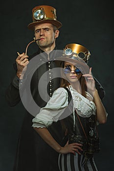 The couple steampunk. A man with a pipe and a girl with glasses