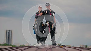 Couple steeplejacks are showing thumbs up at the roof agains the sky