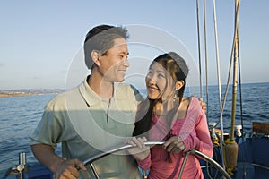 Couple at steering wheel of sailboat