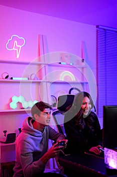 Couple streamer lover boy and girl use joystick for playing video game together hobby in the weekend at entertainment violet neon