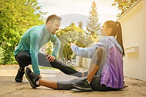 Couple stretching after workout . She sitting on the sidewalk.