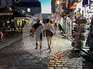 Couple strolls nighttime Montmartre cobblestone street