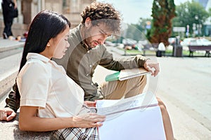 couple of students are talking sitting on the steps .