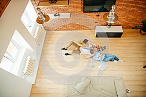 Couple studying while lying on floor at home