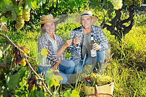 Couple of winegrowers tasting white wine in vineyard