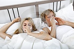 Couple suffering from cold lying on bed