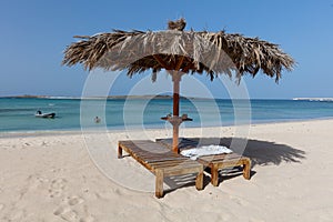 Couple of sun beds and a parasol on a sandy beach