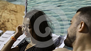 Couple sunbathing near pool. Clip. Beautiful man and woman lying on sunbeds outdoors under the shining sun.