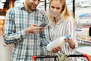 Couple in supermarket reading shopping list