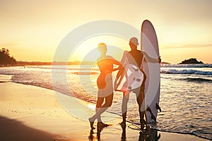 Couple surfers stay on sunset ocean beach