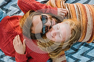 Couple in sweaters chilling and hugging on blanket outdoors in