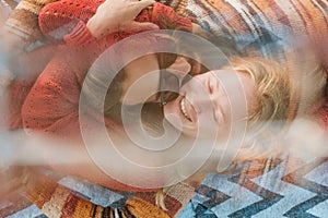 Couple in sweaters chilling and hugging on blanket outdoors in