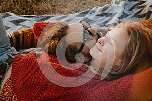 Couple in sweaters chilling and hugging on blanket outdoors in