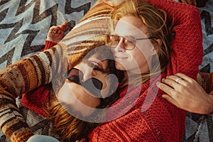 Couple in sweaters chilling and hugging on blanket outdoors in