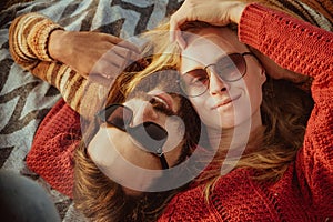 Couple in sweaters chilling and hugging on blanket outdoors in