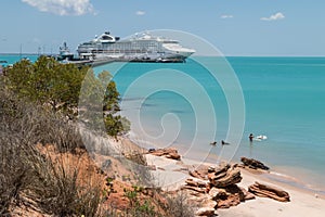 Couple swimming with dogs modern cruise ship tied up to jetty.