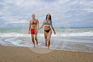 Couple in swimwear coming out from sea in time of surf