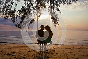 Couple on a swing against of sunset