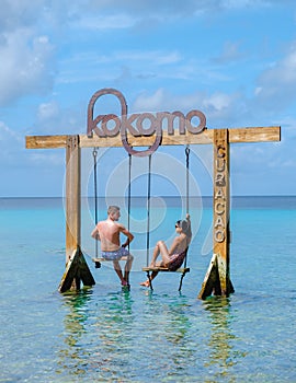 Couple at a swing in the ocean of Curacao Caribbean Island, Kokomo Beach Curacao