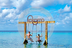 Couple at a swing in the ocean of Curacao Caribbean Island, Kokomo Beach Curacao