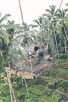 Couple swings in the deep jungle of Bali island.
