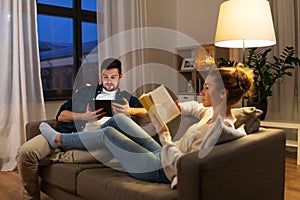 Couple with tablet computer and book at home