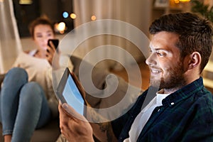 Couple with tablet computer and smartphone at home