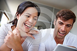 Couple, tablet and funny movie in home, watching and streaming film online on app or website. People, entertainment and
