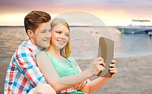 Couple with tablet pc taking selfie over beach