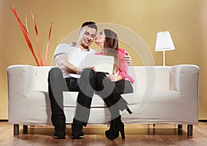 Couple with tablet sitting on couch at home