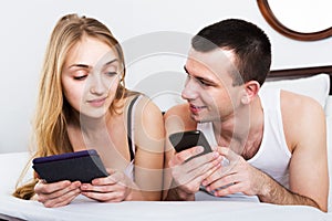 Couple with tablets in bedroom