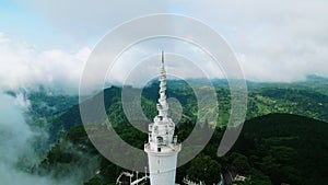 Couple takes selfie dronie on Ambuluwawa Tower with rich green hills, clouds. Scenic landscape, tourists on high