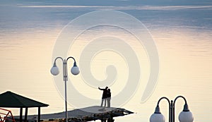 Couple takes selfy on a pier on a lake prespa in macedonia.sunset over lake .