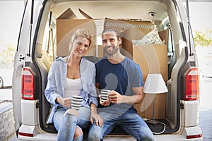 Couple Taking A Break In Back Of Removal Truck On Moving Day