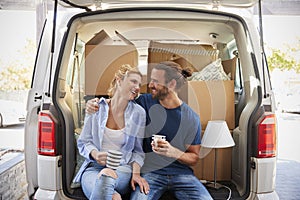Couple Taking A Break In Back Of Removal Truck On Moving Day