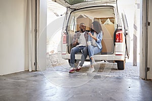 Couple Taking A Break In Back Of Removal Truck On Moving Day