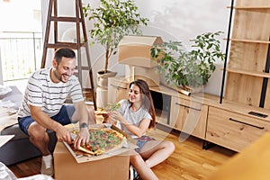 Couple taking a break eating pizza while moving in new home