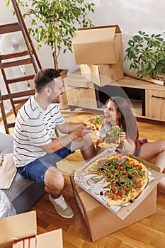 Couple taking a break eating pizza while moving in together