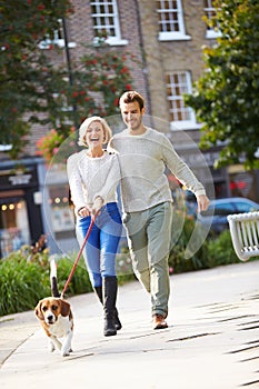 Couple Taking Dog For Walk In City Park