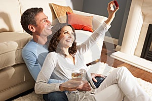 Couple Taking Photograph On Digital Camera At Home