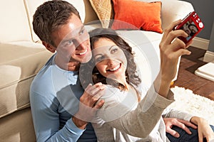 Couple Taking Photograph On Digital Camera At Home