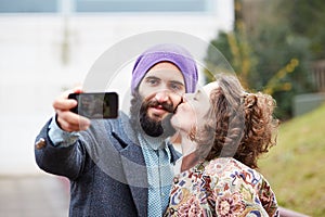 Couple taking a photograph of themselves kissing with a smartphone
