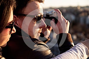 Couple taking pictures of sunset on rooftop of the city