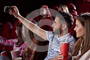 Couple taking self portrait at smart phone in cinema.